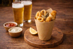 Cuoppo napoletano con fritti croccanti misti su tavolo di legno con accanto due birre chiare e delle salse per fritti