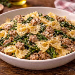 Ciotola in ceramica su tavolo di legno con all'interno delle farfalle con salsiccia e friarielli