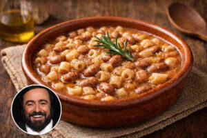 Ciotola in coccio con all'interno una pasta e fagioli profumata e cremosa e in un angolo la foto del cantante lirico Luciano Pavarotti