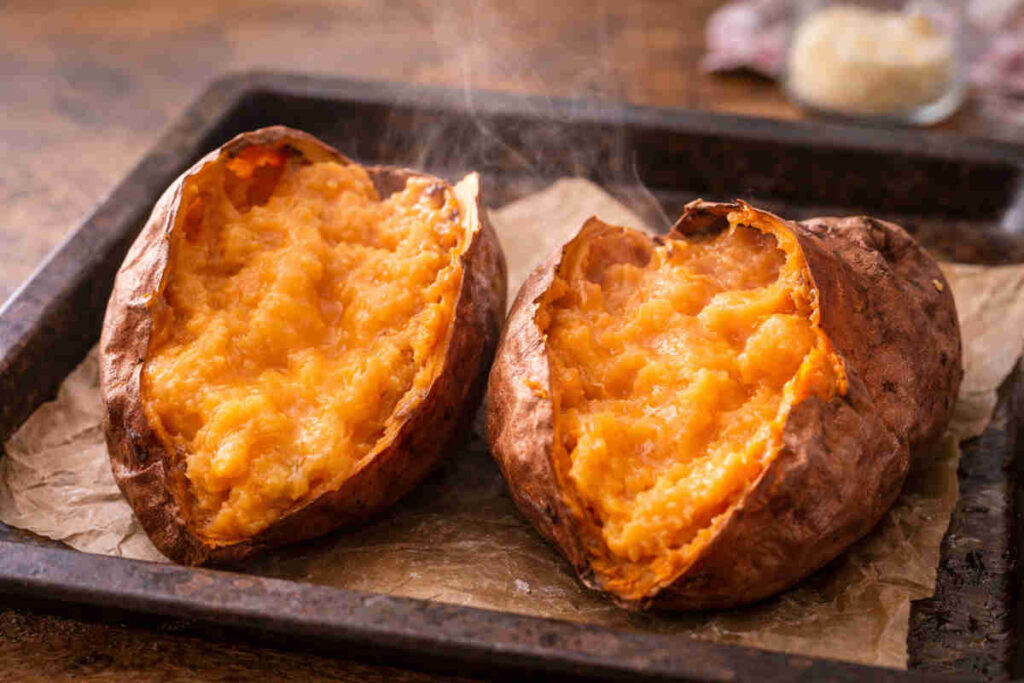 Teglia da forno con carta forno e sopra delle patate dolci cremose appena sfornate