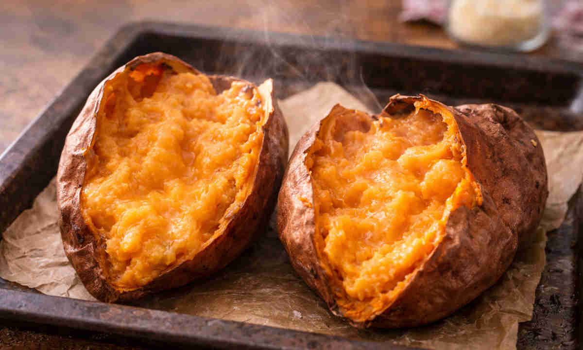 Teglia da forno con carta forno e sopra delle patate dolci cremose appena sfornate